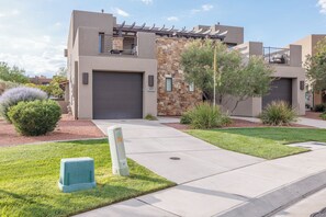 A modern residential building with a garage, stone accents, and well-maintained landscaping.