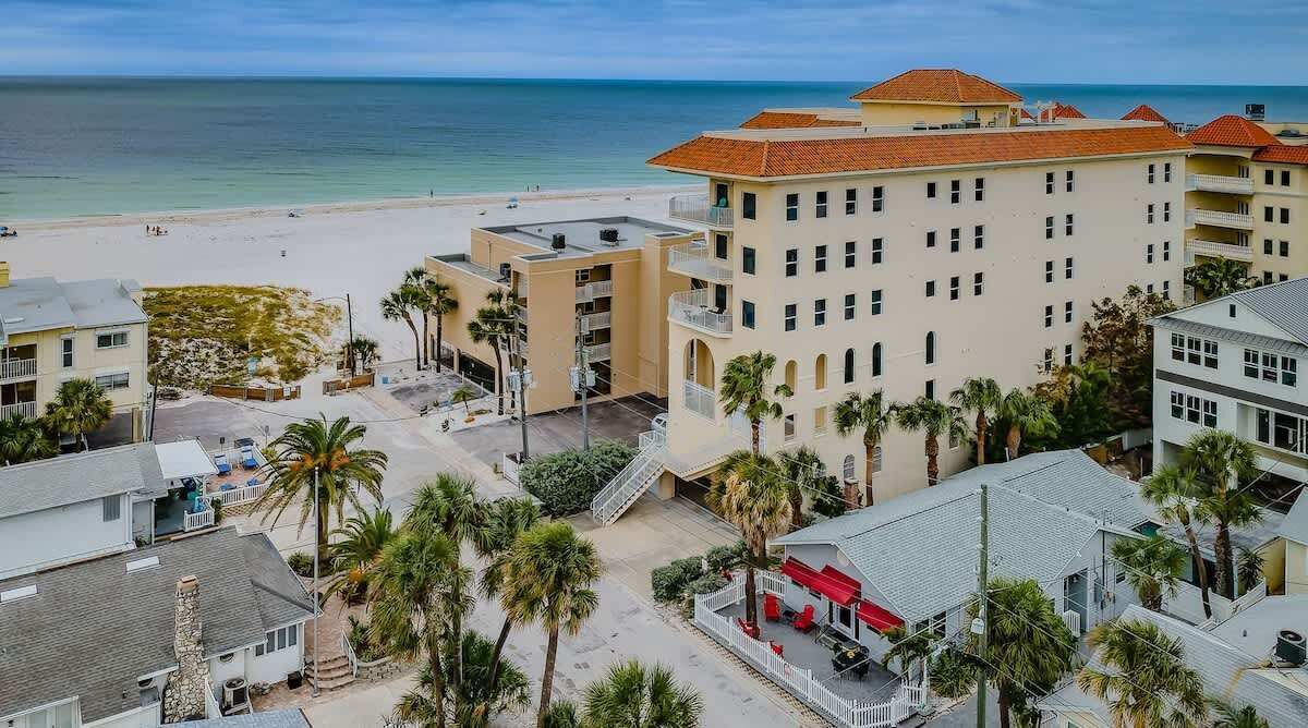 Ein Hotel an der Küste mit mehreren Gebäuden, einem Strand und Palmen.