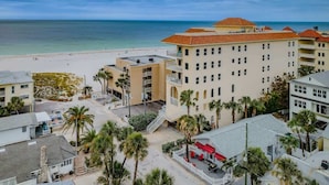 A coastal hotel with multiple buildings, a beach, and palm trees.