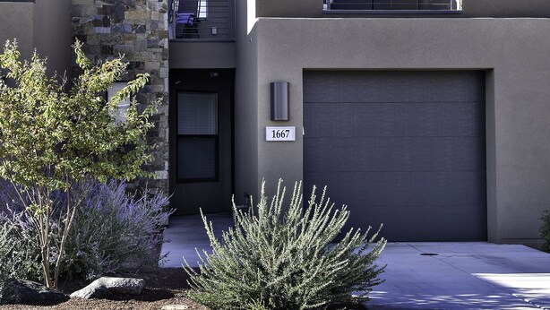 A modern two-story house with a stone facade, a garage, and a well-maintained lawn. - Sweeping Red Rock Views - 4BR close to Pool & Hot Tub (St. George)