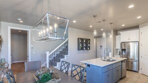 Een moderne keuken met een centraal eiland, roestvrijstalen apparatuur en een trap naar een hoger niveau.