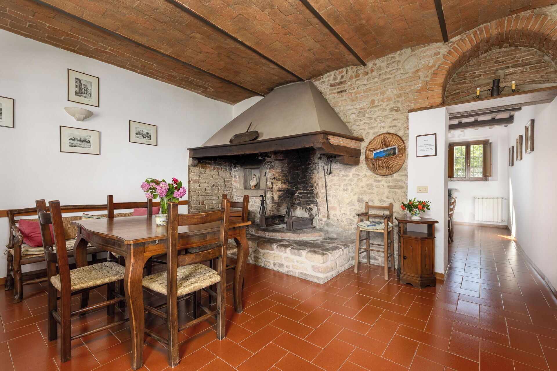 A rustic dining area with a stone fireplace, wooden furniture, and a tiled floor.
