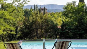 Una piscina con due lettini a righe che si affacciano su un paesaggio montuoso.
