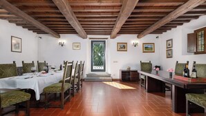 Zona pranzo con travi in legno, un tavolo bianco, sedie e vista attraverso una porta.