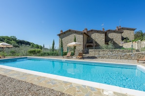 A swimming pool with stone tiles and lounge chairs.