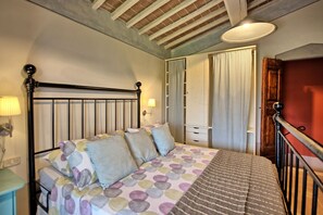 A bedroom with a bed, a nightstand, a lamp, a wardrobe, and a door.