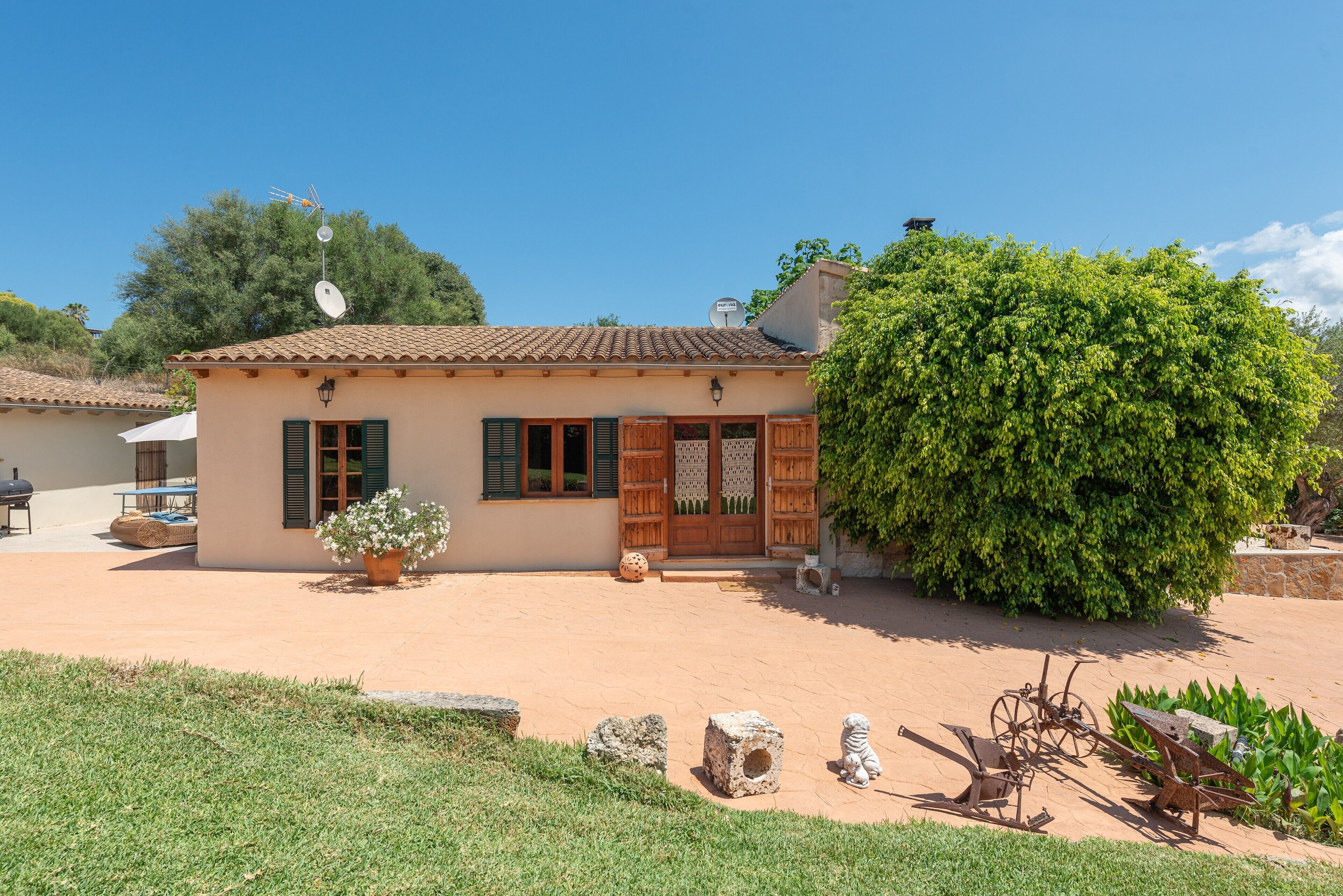 A traditional house with a tiled roof, a wooden door, and a small garden area with a potted plant and a stone bench.