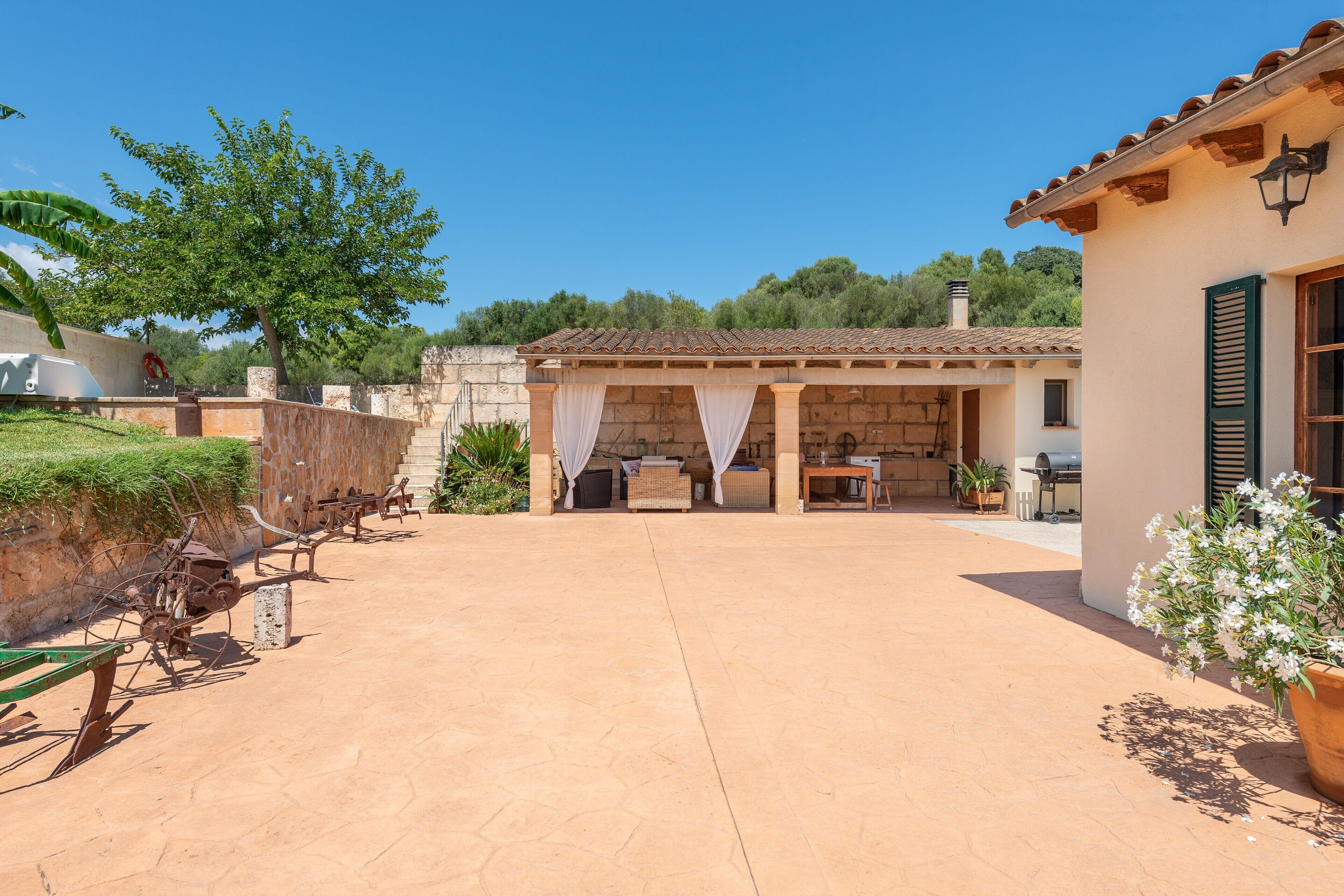 A courtyard with outdoor furniture, a covered seating area, and a building with a tiled roof.
