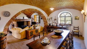 Un coin repas rustique avec une table en bois, des chaises et une cheminée.