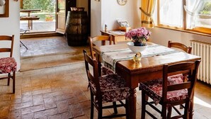 Un coin repas rustique avec des poutres en bois, un sol en pierre et une table dressée pour quatre personnes.