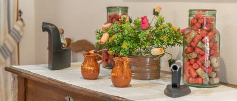 A wooden table with ceramic pitchers, a potted plant, and a jar of corks.