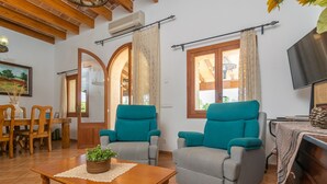 A living room with two teal armchairs, a wooden coffee table, and a TV on a wooden stand.