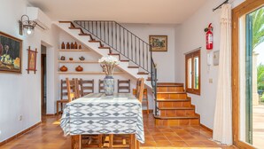 Ein Essbereich mit einem Tisch für vier Personen, einer Treppe und einem an der Wand befestigten Feuerlöscher.