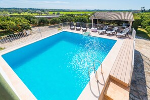 Una piscina rectangular con muelle de madera y sillas de descanso.