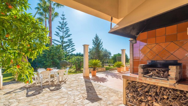 Eine Terrasse im Freien mit Steinplatten, einem Grill aus Ziegelsteinen und Topfpflanzen.