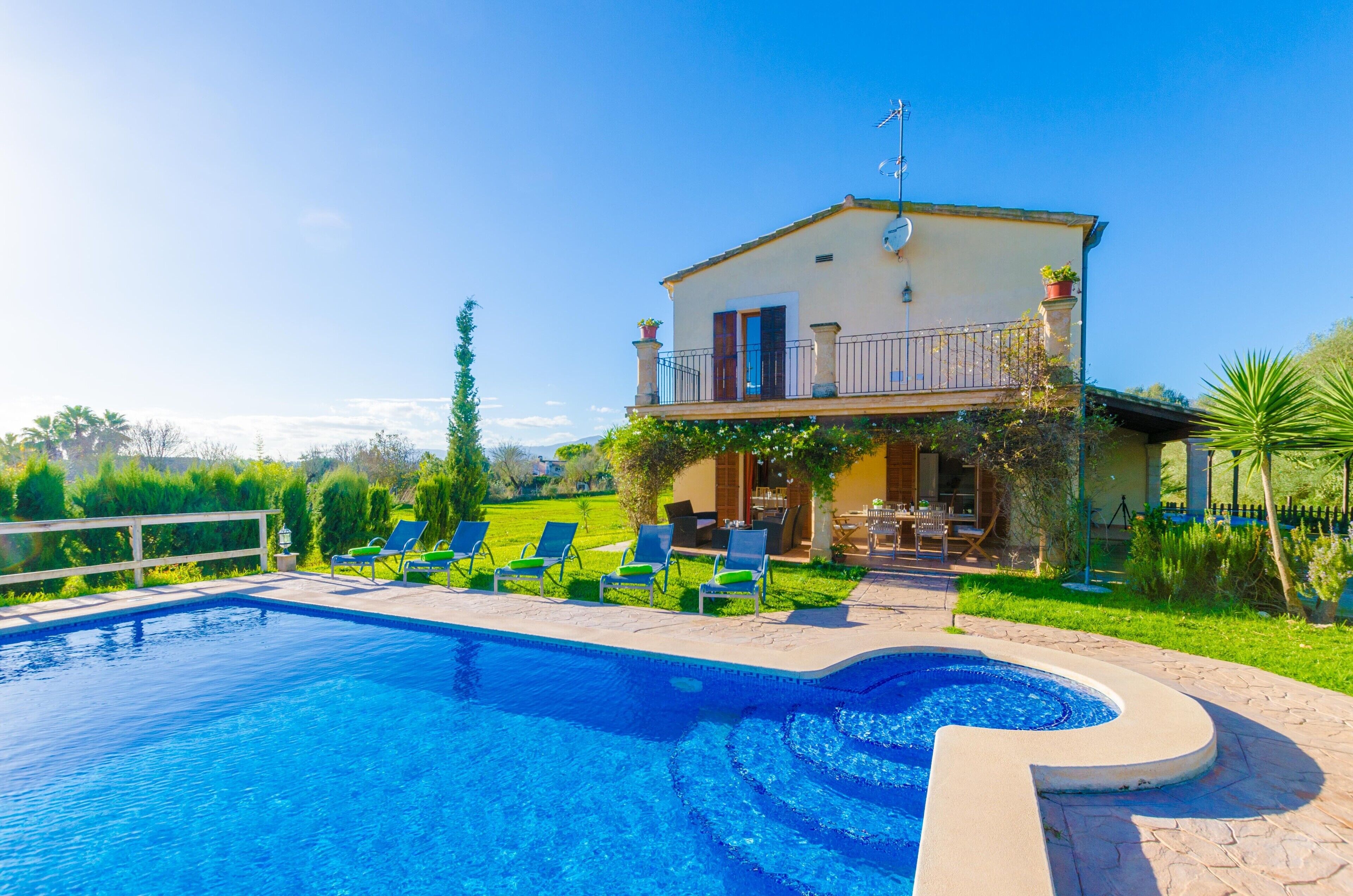 A two-story villa with a swimming pool, outdoor seating, and a well-maintained garden.
