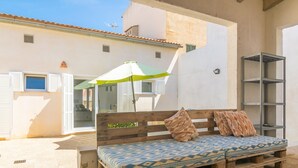 A wooden bench with cushions, a green and white umbrella, and a white building with shutters. - CA NA MARIA (DORANT) - Chalet with terrace in Son Serra de Marina. (Santa Margalida)