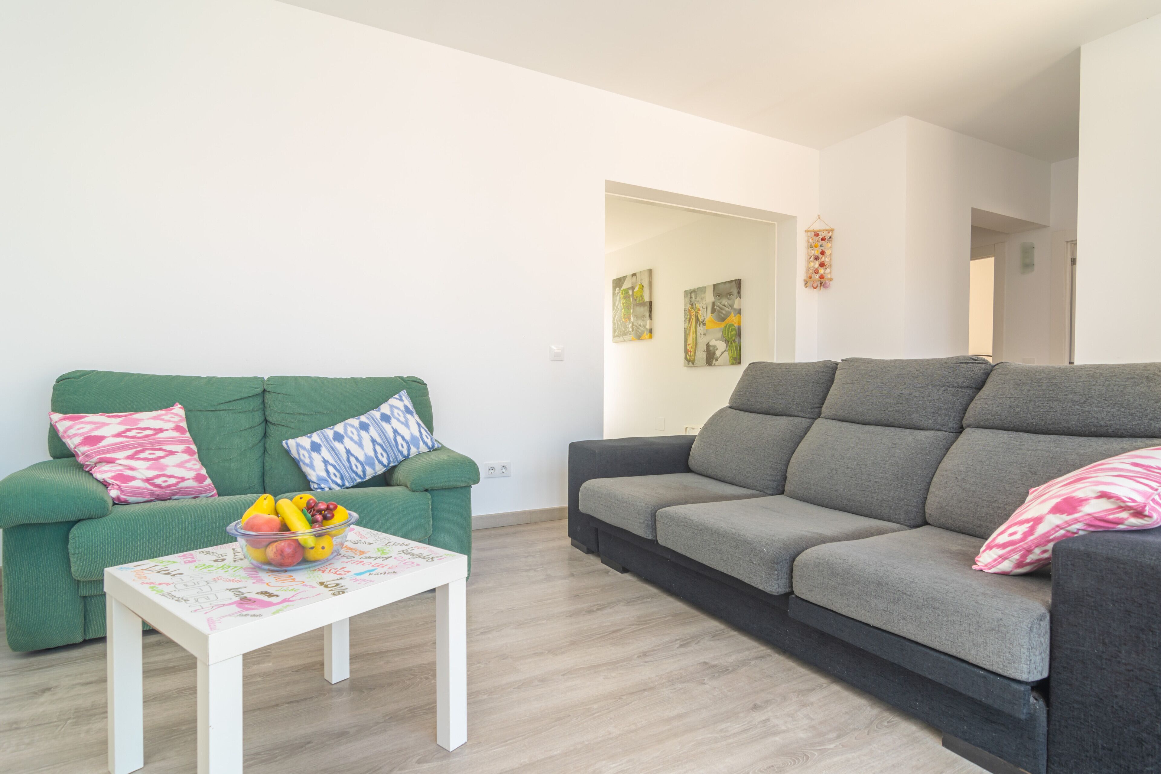 A living room with two sofas, a coffee table with fruit, and a door leading to another room.