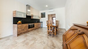 A modern kitchen with a built-in oven, microwave, and a dining area with a wooden table and chairs. - CAS PEIX - ADULTS ONLY  - Villa with private pool in Sa Pobla. Free WiFi (Sa Pobla)