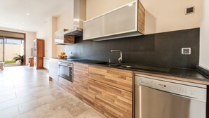 A modern kitchen with wooden cabinetry, a stainless steel dishwasher, and a black countertop. - CAS PEIX - ADULTS ONLY  - Villa with private pool in Sa Pobla. Free WiFi (Sa Pobla)
