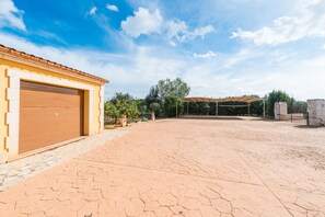 Un amplio espacio exterior con camino de entrada pavimentado, garaje y patio cubierto.