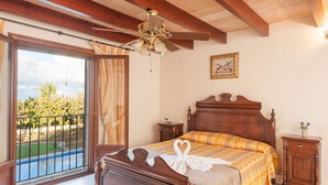 Ein Schlafzimmer mit einem hölzernen Bett, einem Deckenventilator, einem Nachttisch und Blick auf einen Swimmingpool.