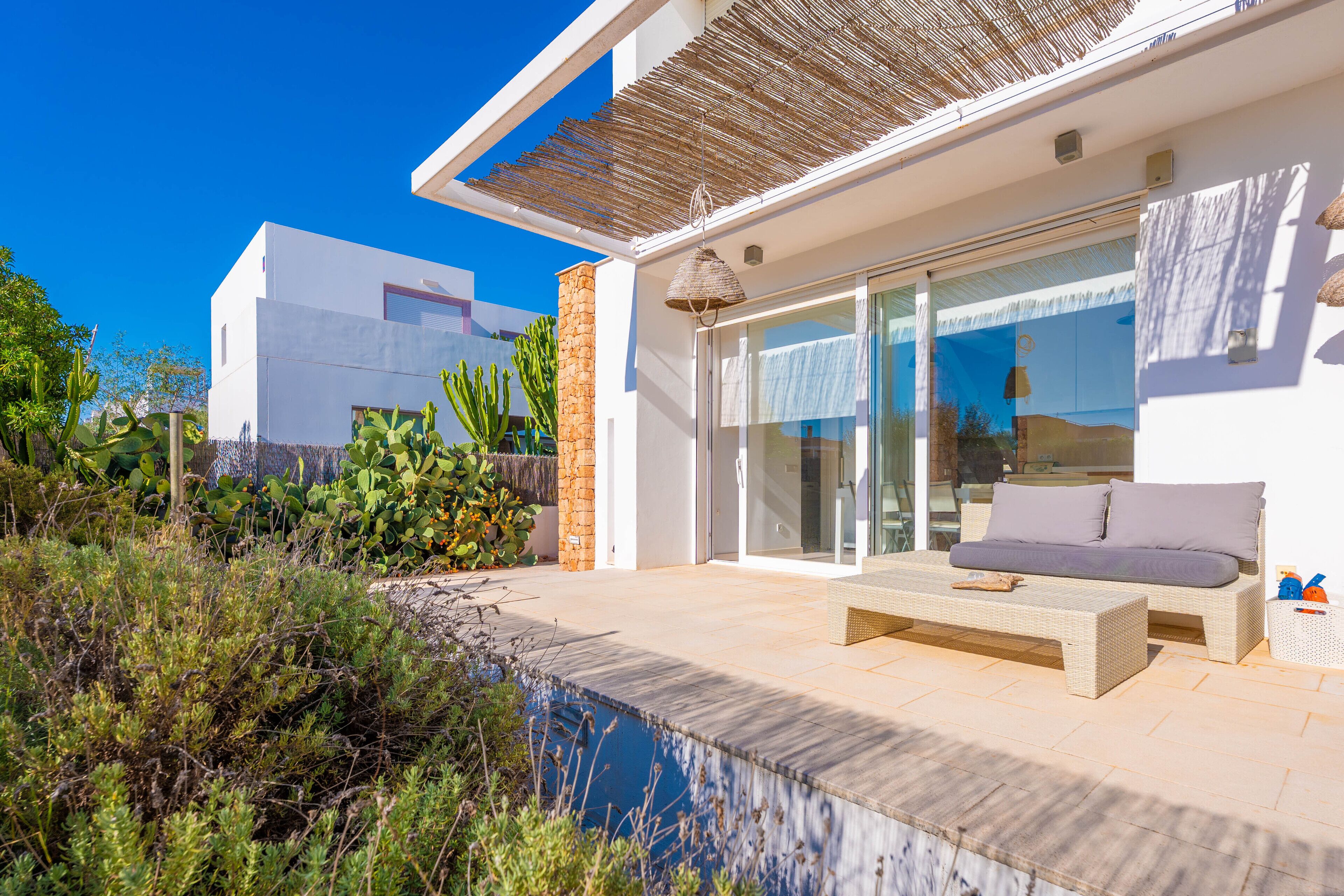 A modern house with a patio, a swimming pool, and a garden with cacti.