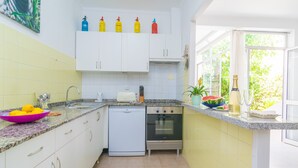 Eine kompakte Küche mit weißen Schränken, einem Geschirrspüler, einem Backofen und einer Arbeitsplatte aus Granit.