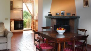 A dining area with a fireplace, a table with chairs, and a view of the kitchen and balcony. - Lovely apartment with pool, WIFI, A/C, TV, pets allowed, panoramic view, close to Greve In Chianti (Mercatale)