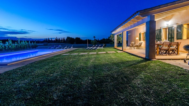 Ein modernes Haus mit Swimmingpool, Sitzgelegenheiten im Freien und einer Terrassenfläche.