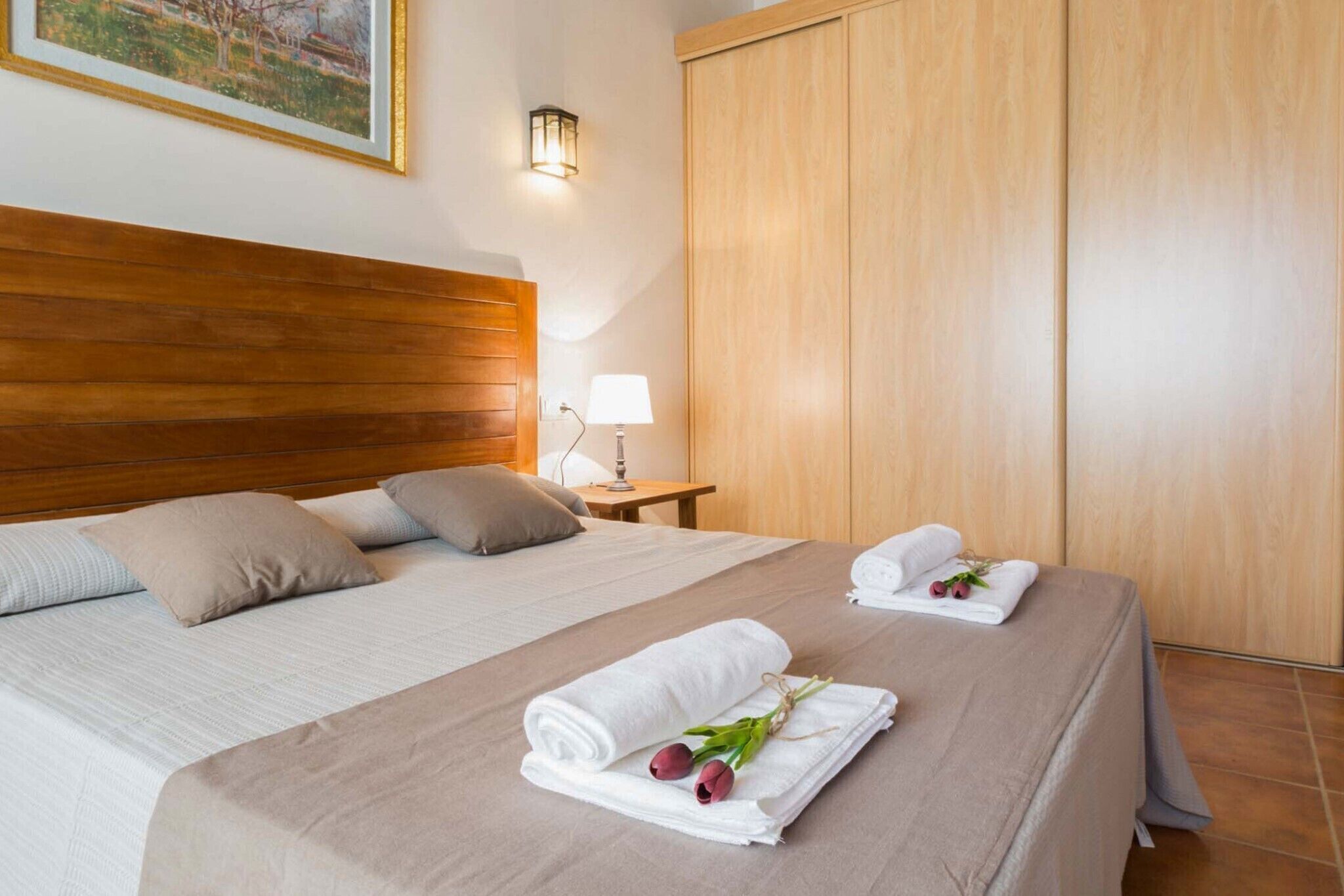 Een hotelkamer met twee bedden, een houten hoofdeinde, een nachtkastje met lamp en een garderobe.