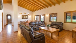 Ein geräumiger Wohnbereich mit Ledersofas, einem Holztisch und einem Essbereich mit Stühlen und Tisch.