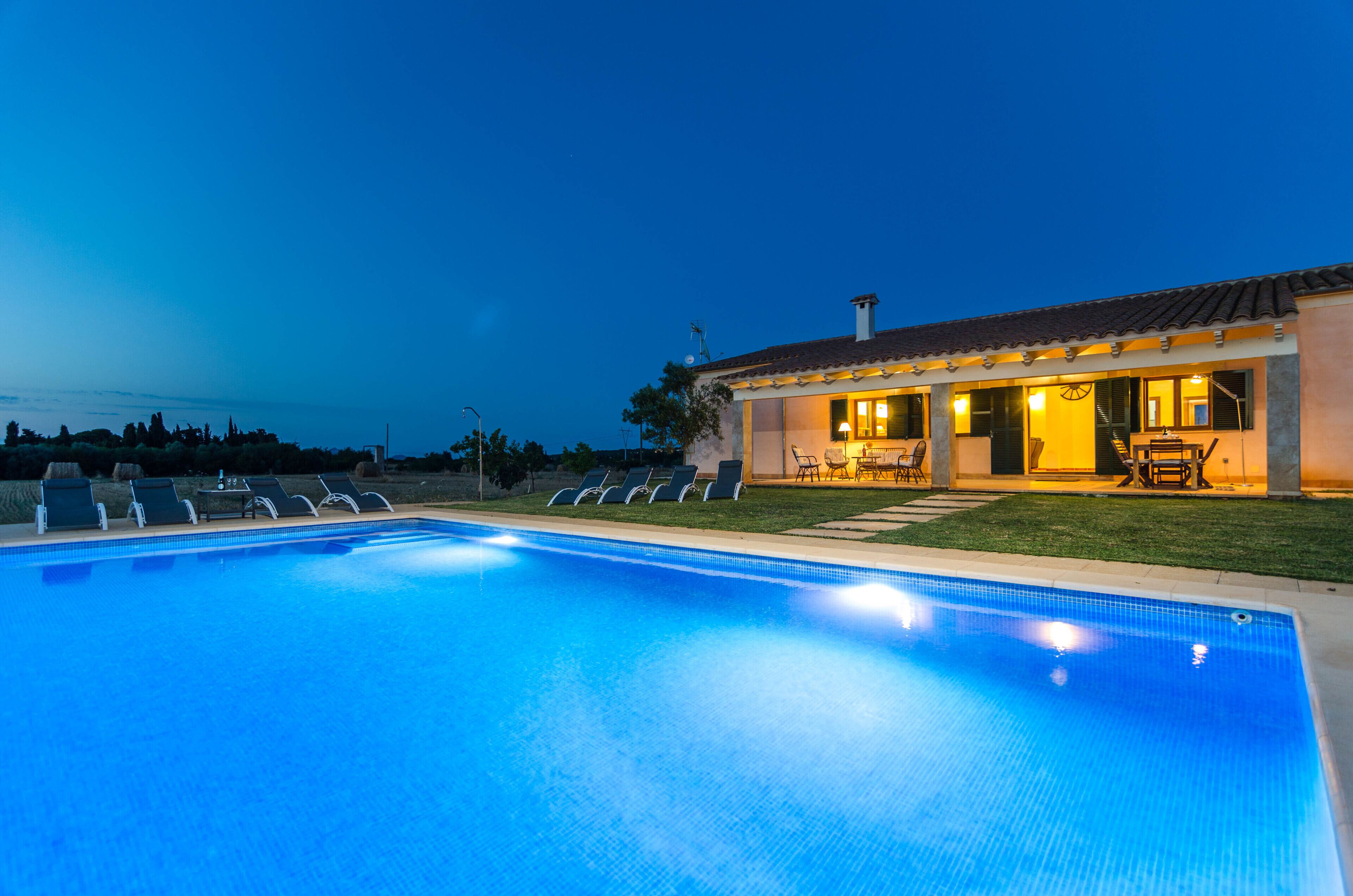 A swimming pool with lounge chairs and a patio area with outdoor furniture.