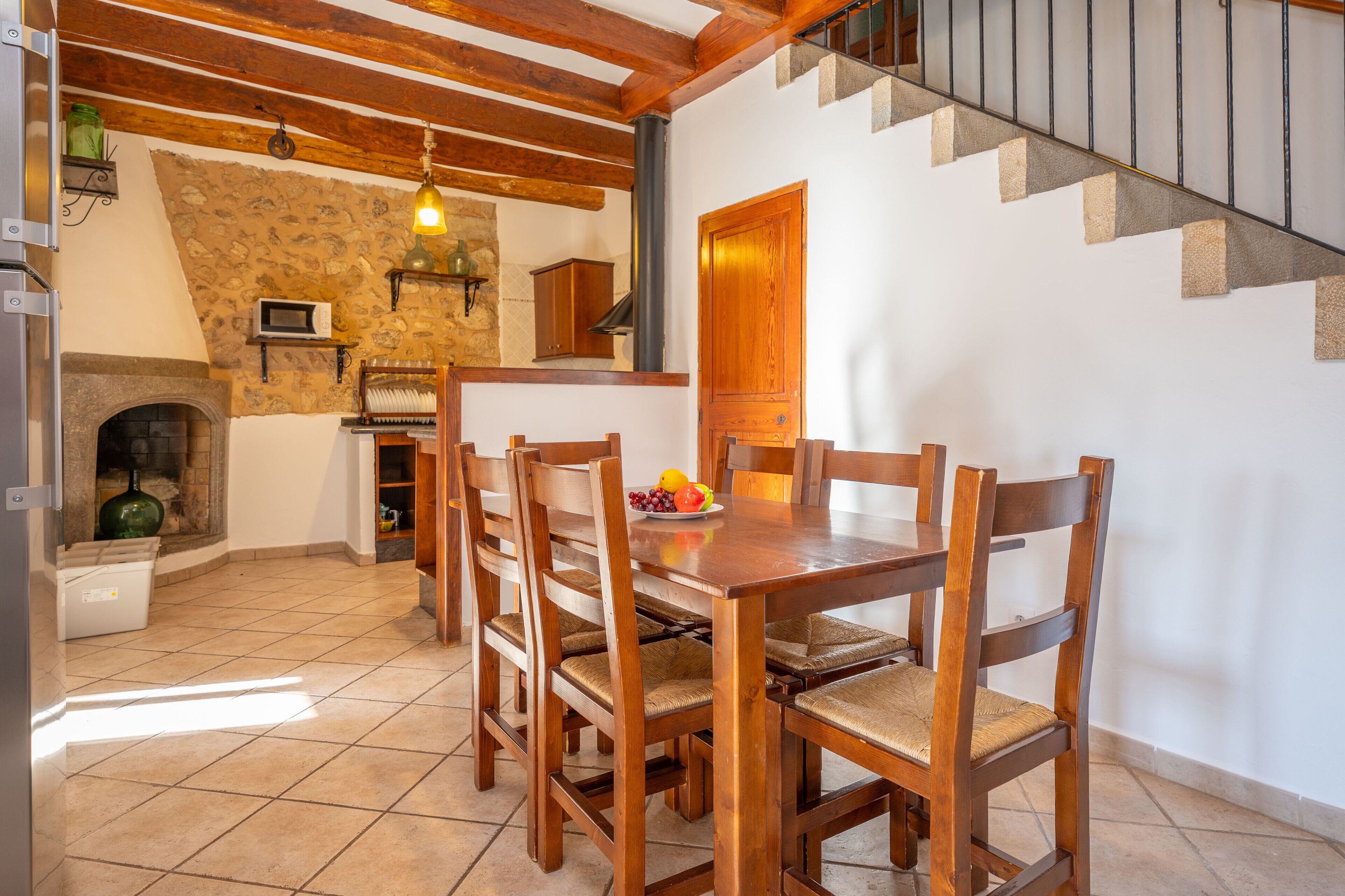 Un comedor con mesa y sillas de madera, una pared de piedra y una escalera.