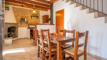 Un comedor con mesa y sillas de madera, una pared de piedra y una escalera.