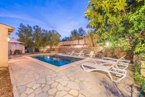 A stone pool with lounge chairs, a stone wall, and a patio area with a table and chairs. - CA N'ABRINES - Beautiful and traditional townhouse with private pool near the mountains. F (Lloseta)