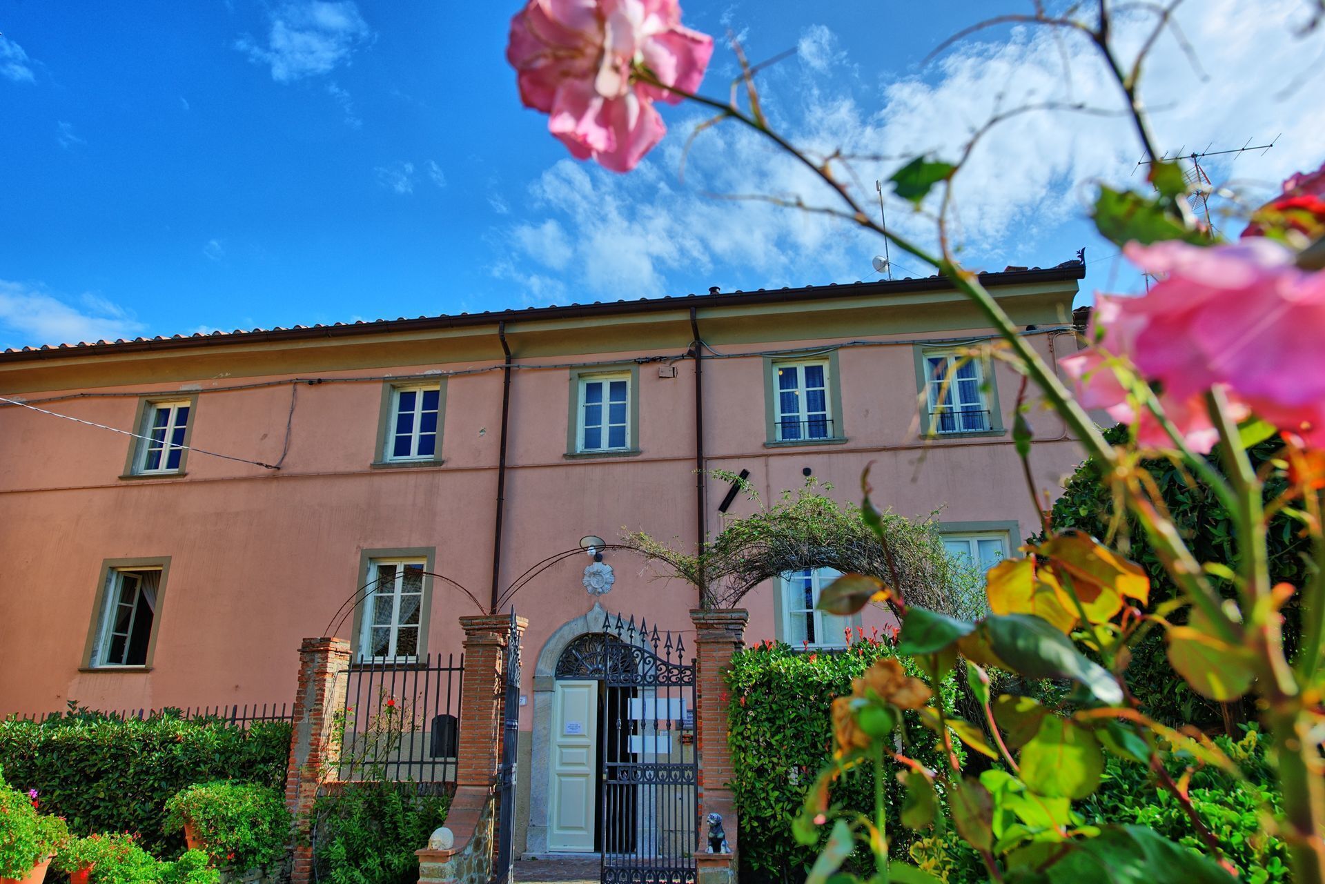 A two-story building with a traditional architectural style, featuring a symmetrical facade, multiple windows, and a central entrance with a decorative gate.