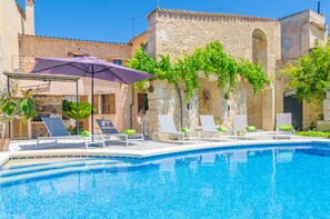 Une piscine avec des chaises longues et un parasol violet.
