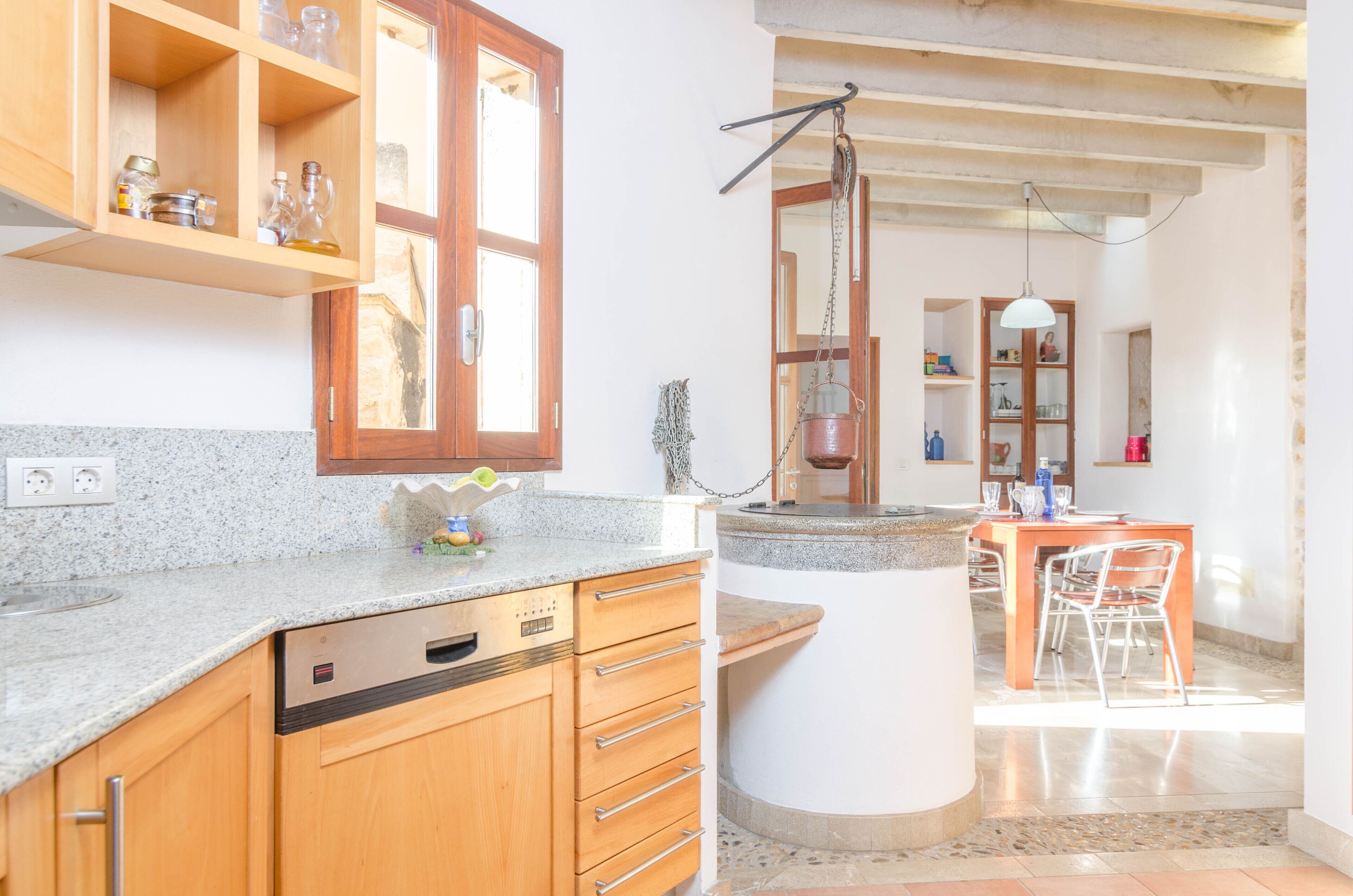 A kitchen with wooden cabinets, granite countertops, and a built-in dishwasher.