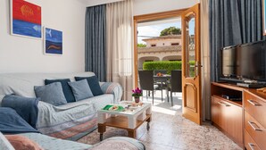A living room with a sofa, coffee table, and TV stand. There is a door leading to an outdoor patio area with a table and chairs. - VILLA ISABEL - Great holiday home with several terraces near the beach. Free WiFi (Muro)