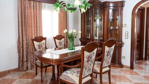 A dining room with a wooden table, floral chairs, a green vase with white flowers, and a wooden cabinet. - CAN BARRET - Chalet for 6 people in Ca'n Picafort. Free WiFi (Ca��n Picafort)