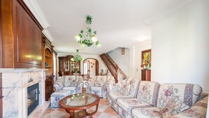 A spacious living room with a fireplace, floral-patterned sofas, a round coffee table, and a chandelier. - CAN BARRET - Chalet for 6 people in Ca'n Picafort. Free WiFi (Ca��n Picafort)