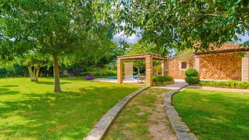 A stone building with a stone facade and a pergola in the garden.