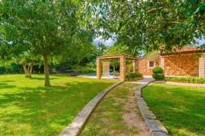 A stone building with a stone facade and a pergola in the garden.