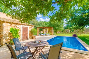 Un espace aménagé au bord de la piscine, avec une pergola, des murs en pierre et un petit jardin.