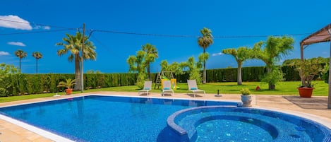 A swimming pool with a curved design, surrounded by lounge chairs and palm trees.