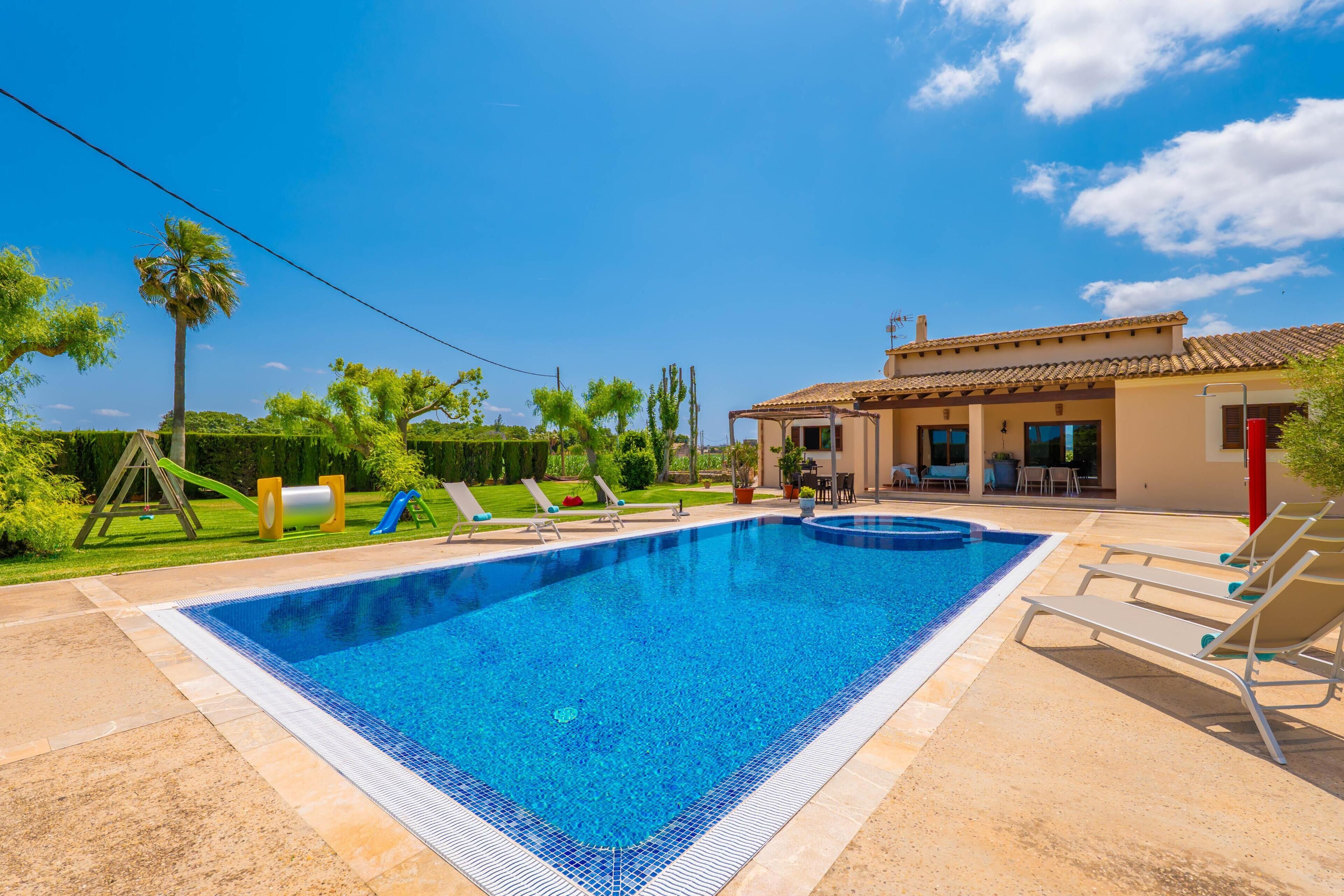 Ein Swimmingpool mit Liegestühlen, einer Terrasse und ein Haus mit einem Ziegeldach.