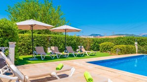 Ein Poolbereich mit Liegestühlen, Sonnenschirmen und freiem Blick auf die umliegende Landschaft.