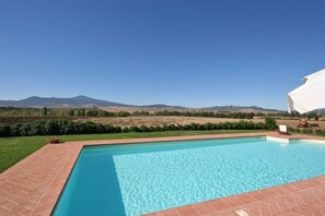 Une piscine rectangulaire à l’eau d’un bleu limpide, entourée d’une terrasse en briques.