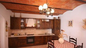 A kitchen with wooden cabinets, a tiled backsplash, a built-in oven, and a dining area with a table and chairs. - Cosy apartment for 4 guests with WIFI, pool, TV and panoramic view, close to Montepulciano (Monticchiello)